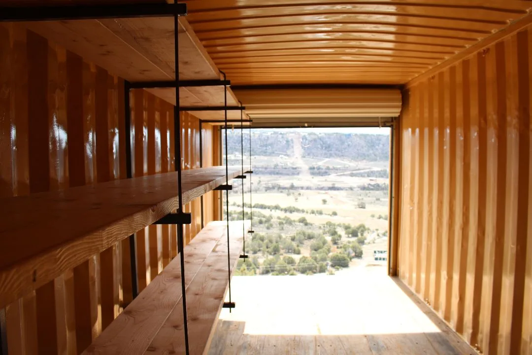Full-length view down a container showing completed multi-tier shelving on both sides with Durango